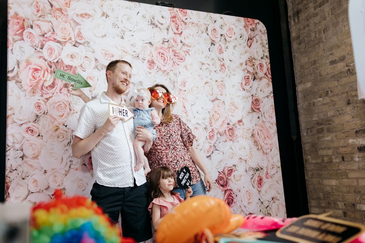 A family with props in front of a floral backdrop